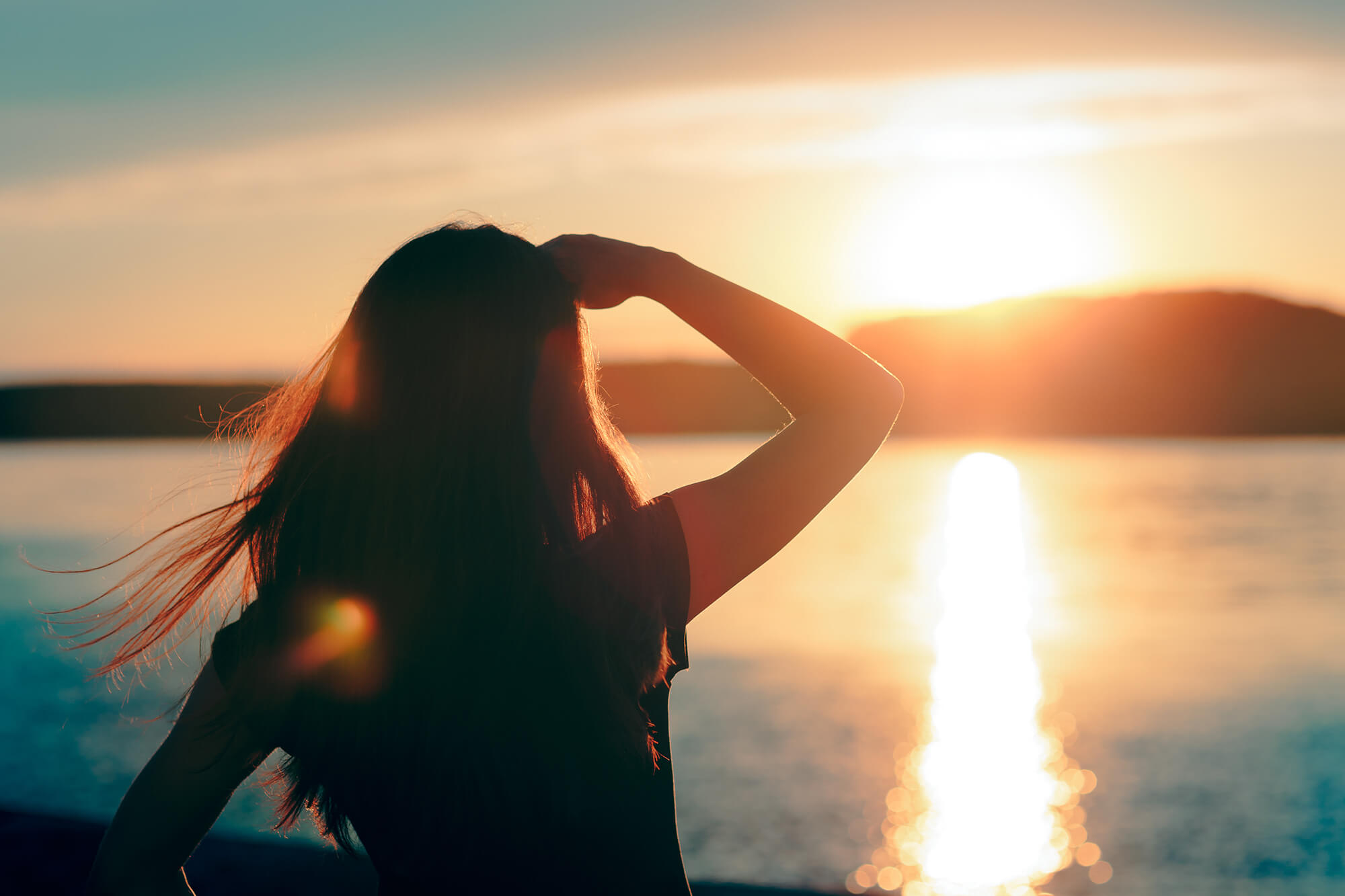 Happy hopeful woman looking at the sunset by the sea